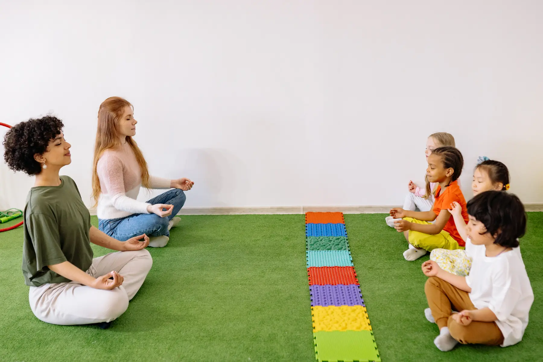 Profesoras de yoga infantil meditando junto a sus alumnos